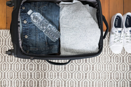 Small overnight weekender black suitcase with wheels packed clothes shoes water explore travel