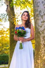 Portrait Caucasian brunette in wedding dress at wedding celebration with bouquet of colorful flowers