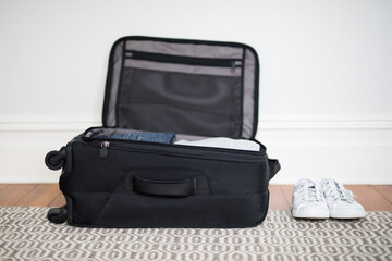 Small overnight weekender black suitcase with wheels packed with clothes,