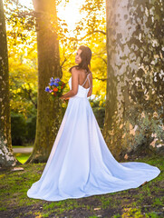 Obraz na płótnie Canvas Caucasian brunette in wedding dress at sunset wedding celebration