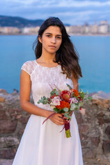 Portrait of smiling young woman in white wedding dress on her wedding day by the sea
