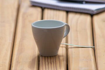 White cup of coffee on wooden table with defocused office work items