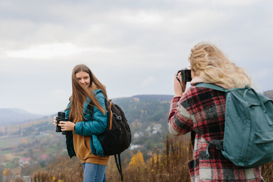 Girl taking pictures of friends in mountains while hiking