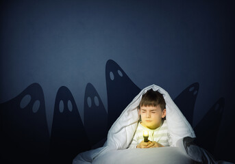 boy under the covers with a flashlight