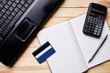 internet banking or shopping concept. calculating tax or payment. laptop, credit card, calculator and notepad on a wooden desk. above view