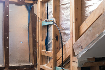 Bathroom being demolished for renovations exposed timber beams studs floor pipes tools electrical 