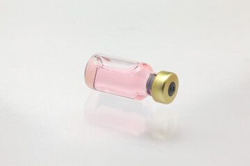 Isolated glass vaccine bottle lying down with colored liquid very close high magnification mockup