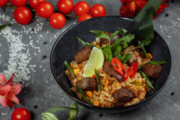 Fried rice with beef and vegetables on a gray textured background