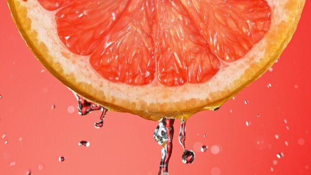 Super Slow Motion of Water Splash on Fresh Backlit Grapefruit Slice. Shot in 1000 fps.
