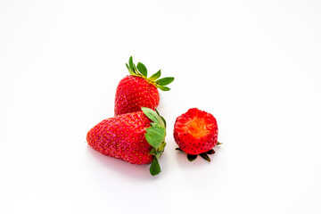 3 isolated strawberries on a white background. One berry has a bite taken from it.