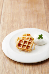 heart shaped waffles on a white plate, wooden table