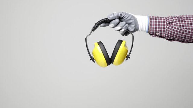 Close up hand of engineer holding earmuff on isolated white background. Engineer equipment concept. 4k resolution.