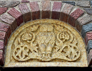 Stylized owl relief carved in stone in an archway.