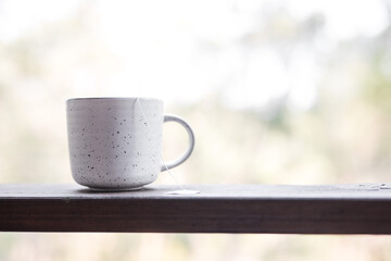 White simple ceramic herbal tea coffee mug herbal tea timber ledge outdoors blurred forest trees natural background