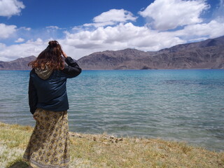 A woman looking out at a beautiful lake, Pangong tso (Lake), Durbuk, Leh, Ladakh, Jammu and Kashmir, India