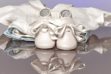 Newborn boots or shoes in white with knotted ties along with baby clothes