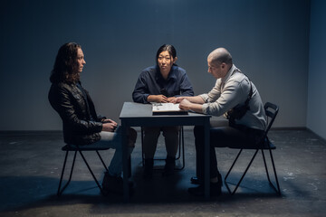 A tough police detective interrogates a crime suspect with a tattooed face in an interrogation room