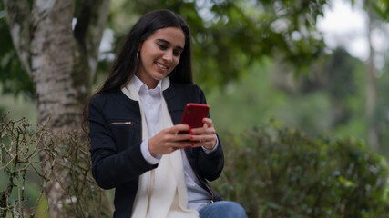 young woman with phone in the park smiling