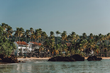 Tropical residence on the paradise beach with palm trees, sandy shore, rocks and blue water of Atlantic Ocean, Las Terrenas, Samana, Dominican Republic 