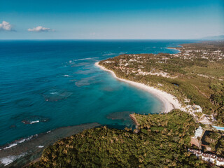 Aerial drone panoramic view of the paradise beach with sandy and rocky shore, palm trees and blue water of Atlantic Ocean, Las Terrenas, Samana, Dominican Republic