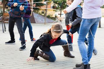 Children games. Happy glad girl goes through the tangled rope