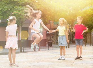 portrait of happy children skipping together with jumping rope on urban playground.