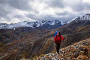 Naklejka premium Girl Backpacking along Scenic Hiking Trail surrounded by Mountains in Canadian Nature. Taken in Tombstone Territorial Park, Yukon, Canada.