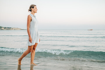 Young woman walking on the beach near the sea