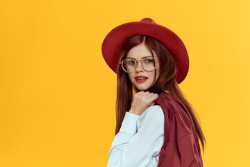 Woman with a jacket on her shoulders red hat white shirt elegant style yellow background