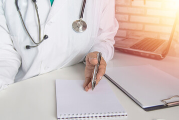 A female doctor talks to a patient, explains the concept of treatment, against the background of a laptop in the medical office