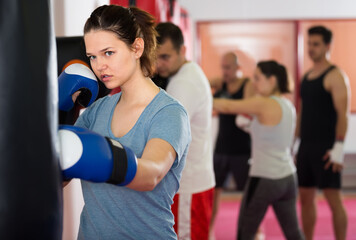 Fototapeta na wymiar healthy sportswoman in the boxing hall practicing boxing punches with boxing bag during training