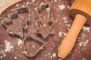 Cookie cutters and rolling pin on dough for gingerbread or other festive cookies. Christmas time