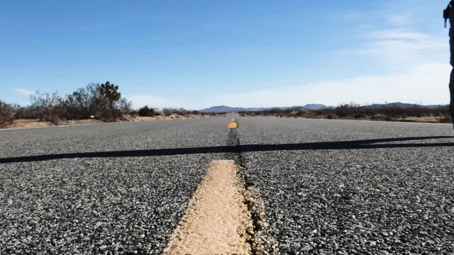 Man walking on an empty road in the middle of the desert, static shot
