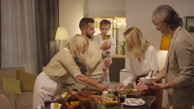 Big multi-generation family with little kid preparing dinner for Thanksgiving holiday celebration