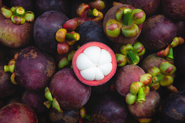 Fresh ripe mangosteen fruits and cross section showing the thick purple skin and white flesh.