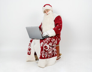 Santa Claus sits at his desk and works at the computer.