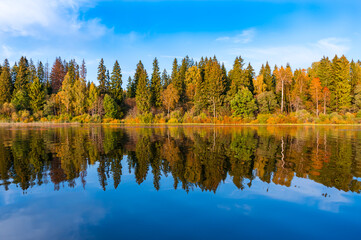 A wonderful view of the autumn forest and its reflection in the lake water. September. Russia