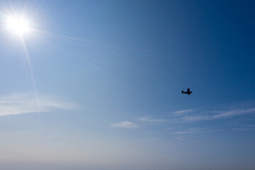 Naklejka na ściany i meble small airplane silhouette in flight against the backdrop of the clear blue sky. aerial photo