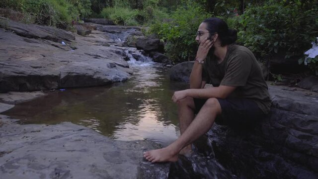 vivek bearded long hair manseating on stone looking around