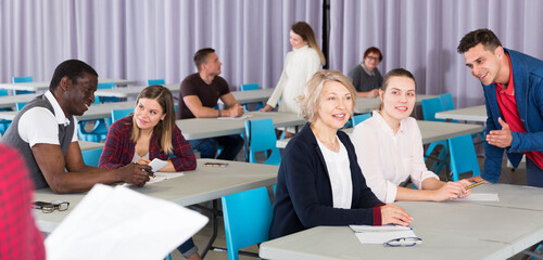 Group of adult education students studying together in class, discussing lesson