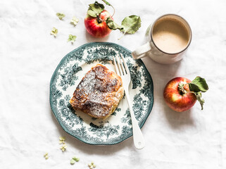 Piece of apple strudel and coffee with cream on a light background, top view. Delicious breakfast, dessert, brunch