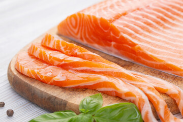 Raw fresh salmon fillet cut into slices and piece on wooden board