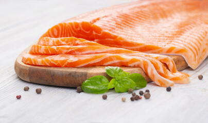 Raw fresh salmon fillet cut into slices and piece on wooden board