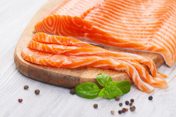 Raw fresh salmon fillet cut into slices and piece on wooden board