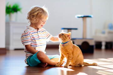 Child playing with cat at home. Kids and pets.