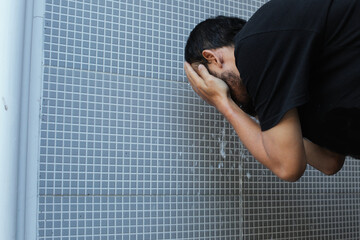 A moslem man take ablution, known as wudu, as one of ritual purification to pray : washing face 