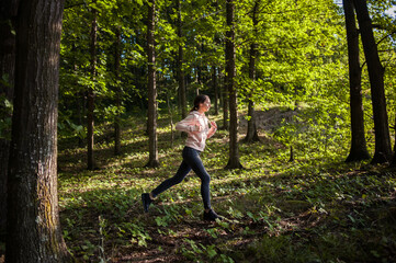 Young woman wearing yoga pants meditating in the woods on a sunny morning.