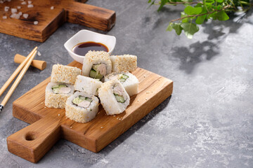 Fototapeta na wymiar Roll made of Fresh cucumber and chicken and salad inside in a gray background. Delicious food. Beautiful still life with a portion of rolls on a wooden board.