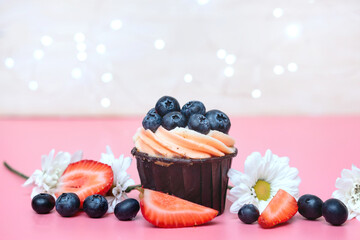 one sweet cupcake with cream and blueberries, decorated with strawberries and flowers