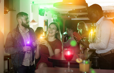 Fototapeta na wymiar Portrait of male bartender shaking cocktail mixer for couple in nightclub